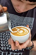 Free pouring of latte art at Doppio Ristretto in Chiang Mai. The artist won several championships in Australia and came in 6th at the world championship in 2011. This is his signature latte art: angel surfing on waves.
