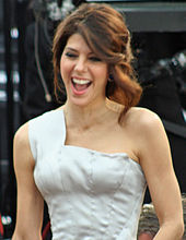 A photo of a brown-haired woman wearing a white dress
