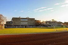 Nordansicht des Gymnasiums mit dem Sportplatz im Vordergrund.