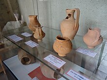Photographie en couleurs d'une exposition de poteries antiques dans un musée.