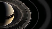 Viene mostrata la metà del sistema saturniano, Saturno tagliato a metà e mostrando gli archi fatti dagli anelli verso l'esterno.