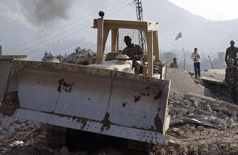 File:US Navy 051107-F-2729L-004 U.S. Navy Equipment Operator 2nd Class Percy Evans, assigned to Naval Mobile Construction Battalion Seven Four (NMCB-74), removes debris from the fallen Government Girls High School at the Dewan Tent.jpg