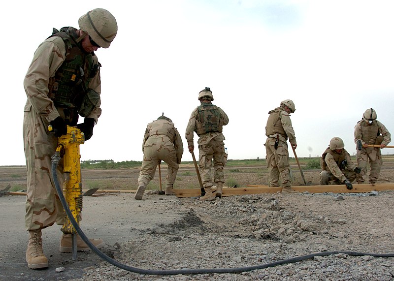 File:US Navy 060520-N-9712C-003 Builder 3rd Class Darin Errington breaks apart asphalt with a jackhammer as other Seabees prepare forms for a concrete pour on a road repair project.jpg