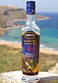 A bottle of Maltese carob liqueur with the north coast of Gozo Island in the background (Malta, April 2009).jpg