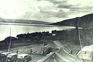 Group of tents and motor cars with Sea of Galilee in background