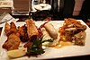 Hearty Bavarian food on a fancy plate.  Left to right: ''Schnitzel'', pork belly (''Schweinebauch'') with red cabbage (''Blaukraut''), ''Weißwurst'' with mashed potatoes (''Kartoffelpüree''), ''Bratwurst'' on sauerkraut