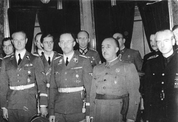 The Spanish Head of State, Generalíssimo Francisco Franco, is host to the Third Reich officials Karl Wolff (lt.), Joachim Peiper (ctr.), and Reichsfüh