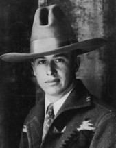 A young man in a cowboy hat, casual jacket, and shirt and tie
