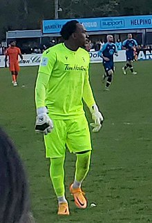 Goalkeeper dressed in a green kit looking to his right during a match