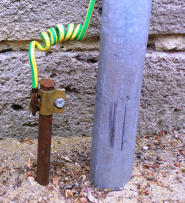 A typical earthing electrode (left of gray pipe), consisting of a conductive rod driven into the ground, at a home in Australia. Most electrical codes