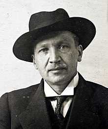 A picture of Kullervo Manner, chairman of the Finnish People's Delegation and last commander-in-chief of the Reds, looking straight at the camera with a suit and a hat on.