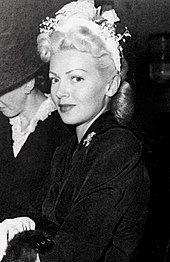 Woman wearing flowered hairpiece looking into camera