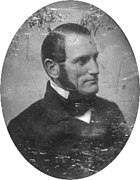 A black and white head-and-shoulders photographic portrait of Parkman. He faces to the right, sports long sideburns, and wears a dark suit and tie. The photograph has scratches and other damage.