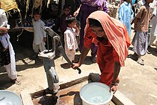 A young woman pumps water from a handpump in her village.