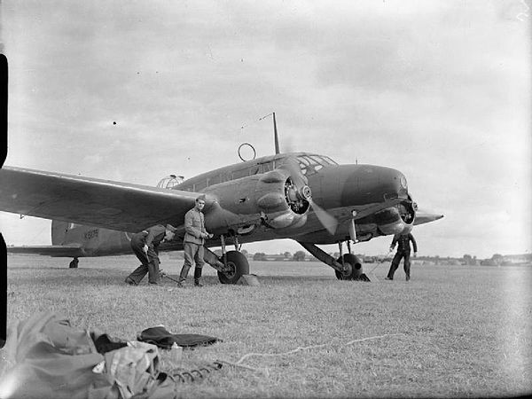 The wheel chocks are removed from Avro Anson Mark I, K6175, of No. 320 (Dutch) Squadron RAF before taking off on a patrol from Carew Cheriton, Pembrok