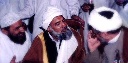 Shahi at an event at Imam Bargah-e-Noor-e-Iman Mosque, in Karachi, Pakistan. He is seen here speaking to two religious clerics from different sects within Islam: Shia Islam and Sunni Islam.