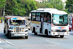 Two white buses side by side, one larger than the other