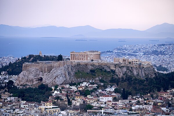 The Acropolis of Athens as seen from Mount Lycabettus The wooded Hill of the Nymphs is half-visible on its right, and Philopappos Hill on the left, im