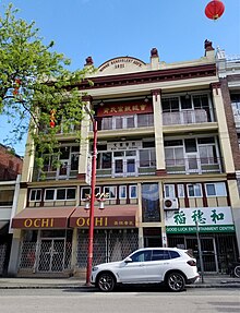 Exterior shot from the street of the Wongs' Benevolent Association Building, where the Mon Keang School is housed on the third floor, in the day.