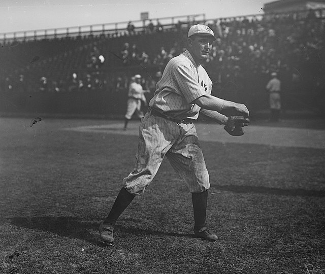 A black-and-white image of a man in a white old-style baseball uniform