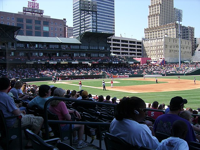 A baseball game being played on a green field with fans watching on