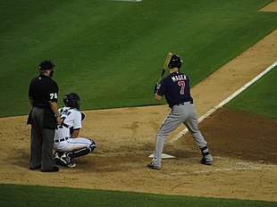 Catcher James McCann (in white uniform) of the Detroit Tigers using his right hand (obscured) to give signs to his pitcher, in a 2015 game against the Minnesota Twins. Baseball catching giving signs.jpg