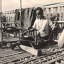 A Chakma woman weaving on balcony of bamboo house in Bandarban