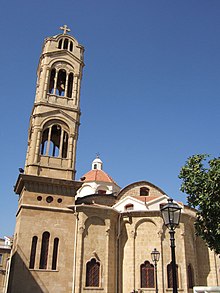 Photo d'une église grecque orthodoxe à Nicosie, bâtiment en pierre surmonté d'un clocher et d'une croix grecque et en fonds un ciel bleu.
