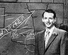 Meteorologist Harry Volkman from 1956 standing in front of a weather map of Oklahoma and adjacent states, presenting a weather report on-air.