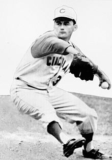 A man wearing a baseball uniform with "Cincinnati" written across the chest and a "C" on the cap in the midst of pitching a baseball