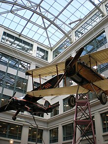 A Stinson SR-10 Reliant (black) and a De Havilland DH-4B (wood) hanging from the ceiling at the National Postal Museum in Washington, D.C.