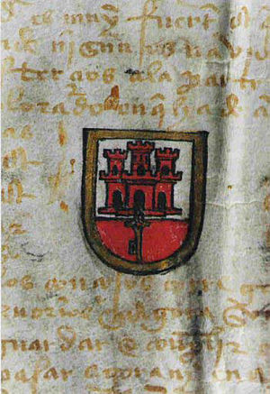 A parchment document with Latin writing in yellow ink and an armorial device in the middle, showing a red castle with a key hanging below on a white and red background, surrounded by a gold shield