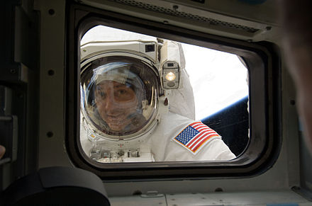 Mission Specialist Michael Massimino peers into the orbiter's aft flight deck window during the fourth spacewalk of the mission.