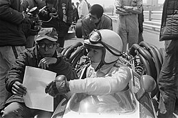 Photo de Yoshio Nakamura, accroupi près de la monoplace Honda dans laquelle John Surtees est installé.