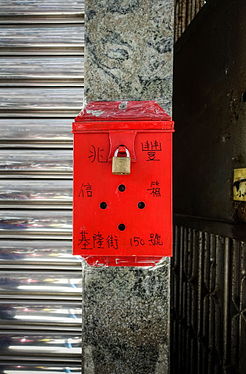 A traditonal red wall-mount metal mailbox, Hong Kong.