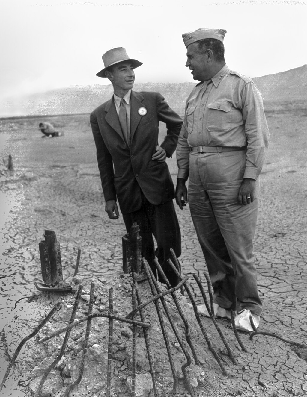 Oppenheimer and Leslie Groves in September 1945 at the remains of the Trinity test in New Mexico. The white canvas overshoes prevented fallout from sticking to the soles of their shoes.[188]