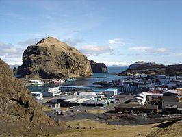 Het stadje Vestmannaeyjar op het grootste eiland Heimaey, gezien vanaf de hellingen van de berg Háhá. De berg links heet Heimaklettur. Achter het lavaveld rechts is Bjarnaey te zien.