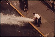 Een schoonmaker gebruikt een brandkraan om afval weg te spoelen. 172nd street, NYC, 1973