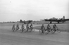 B-17s of the 92d Bombardment Group at RAF Alconbury 92d Bomb Group riding bikes past B-17s.jpg