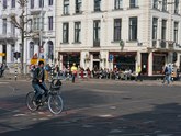 Biking woman in the sunlight over the crossing of the streets Plantage Middenlaan & Plantage Kerklaan in Amsterdam. Free city photo by Fons Heijnsbroek, 28 April 2022