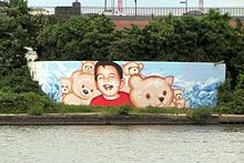 Photo of a mural for Alan Kurdi on a wall above a river