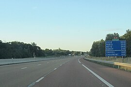 Vista autostrada con segnale di avvertimento distanza sovrastato dai segnali E21 ed E17.