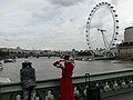 Street artists on Westminster Bridge in London and London Eye in the background