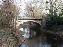 Photographie en couleurs d'un pont en pierre au-dessus d'une rivière.