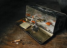 Hitam kotak logam berbalik pada sisinya dan dibuka untuk menunjukkan instrumen yang digunakan untuk penggunaan heroin, termasuk sendok perak dan jarum suntik