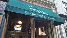 Fotografie vchodu do budovy s „Hobo's Restaurant and Lounge“ vytištěnou na zeleném potahu; v okně je označení pro video loterii