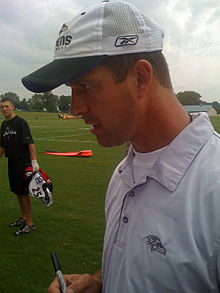 A man with a hat holding a marker.