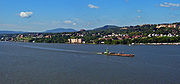 A city on a slope over a body of water with larger buildings at the left and center right