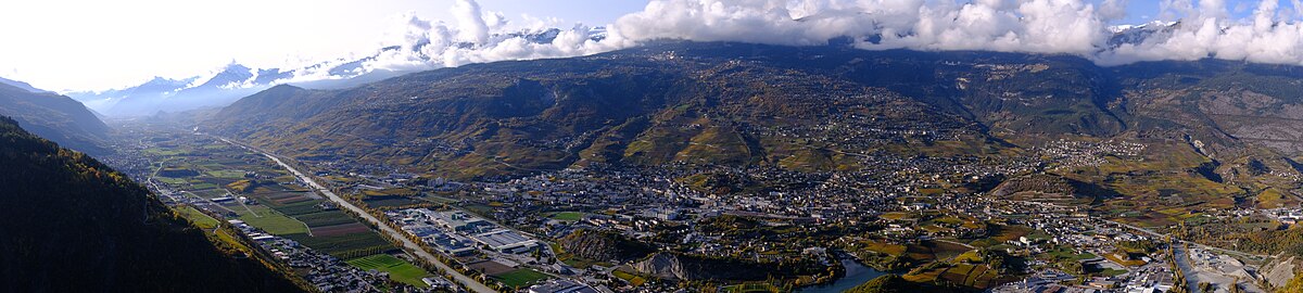 Vue de haut de plusieurs villages et villes et d'une vallée. Un fleuve parcours le long de la vallée.