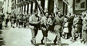 Partisans parade through the streets of Milan immediately after the Liberation. In the center, with the Italian tricolour flag, Eva Colombo Partigiani sfilano per le strade di milano.jpg